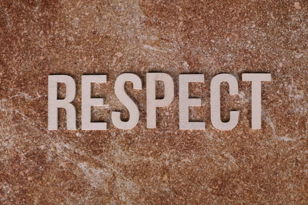 Wooden letters spelling 'RESPECT' on a textured stone surface, conveying a message of dignity and value.
